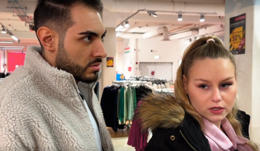 Blonder Frau mit Pferdeschwanz und rosa Schal steht angespannt neben einem dunkelhaarigen Mann in einem Bekleidungsgeschäft. | © Screenshot RTLzwei/RTL+ 