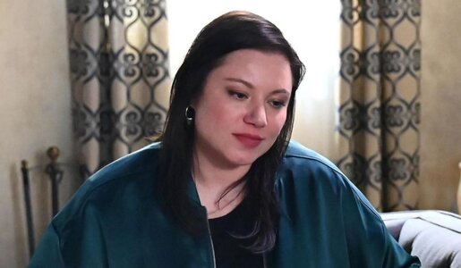 Nachdenkliche Frau mit langen dunklen Haaren und silbernen Creolen sitzt vor gemusterten Vorhängen auf einem Sofa. | © RTL / Julia Feldhagen