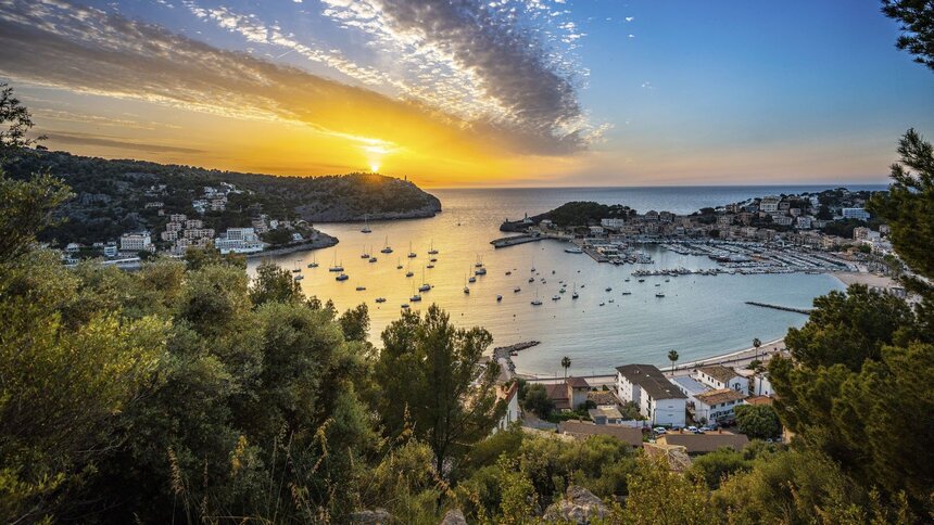 Blick auf eine idyllische Hafenbucht mit vielen Segelbooten im goldenen Licht eines dramatischen Sonnenuntergangs über dem Meer. | © HR / Joel Hess
