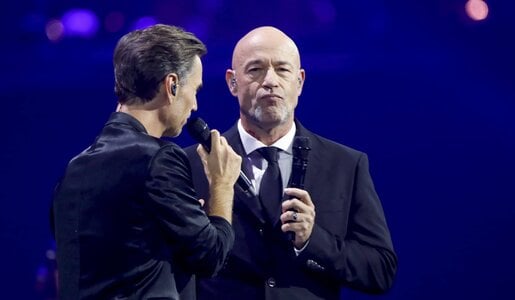 Ein junger Mann mit braunem Haar und ein glatzköpfiger alter Mann stehen sich auf einer Bühne mit Mikrofonen gegenüber. | © IMAGO / pictureteam / Matthias Gränzdörfer