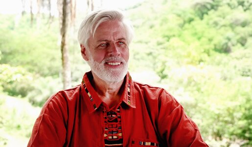 Älterer Mann mit vollem weißen Bart und lachendem Gesicht trägt ein rotes Hemd vor grüner Landschaft. | © RTL/Maria Heymer